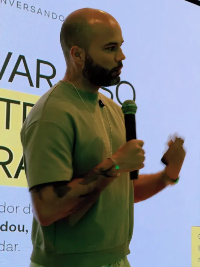 Dante Araújo de perfil, microfone na mão, durante palestra